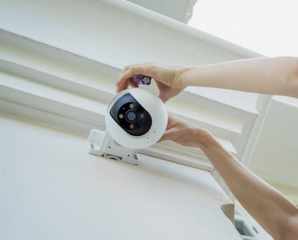 A technician installs a CCTV camera on the facade of a residential building